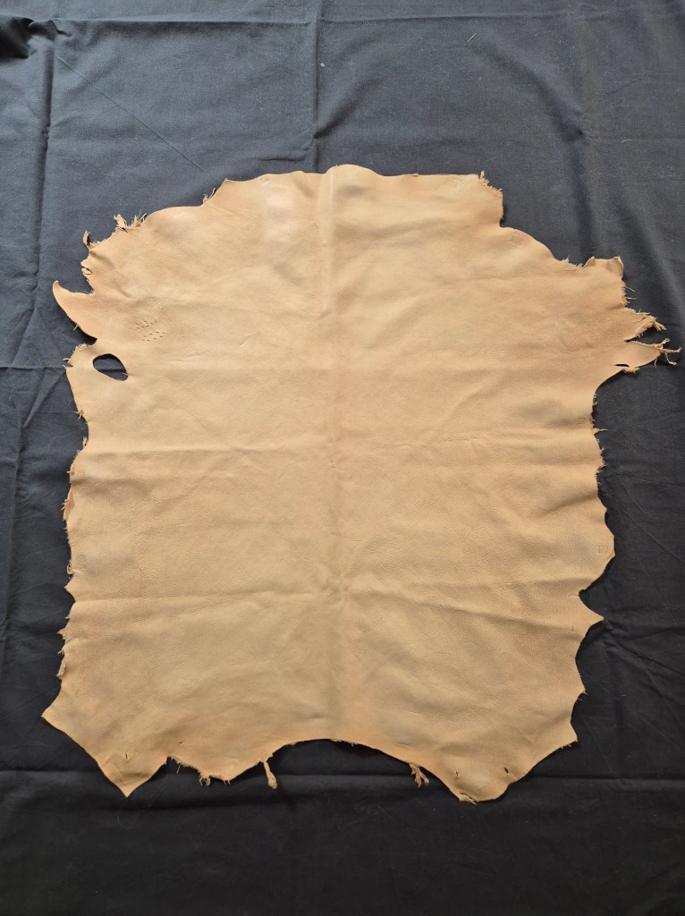 Naturfärgat getskinn mot en mörkgrå bakgrund.