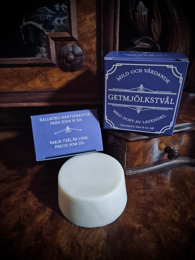 En bild på ett par tvålaskar och en vit, rund tvål. På asken står "Mild och vårdande getmjölkstvål med doft av lavendel."