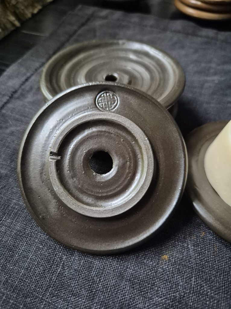 Stengods med svartbrun glasyr (svårfångad på bild). Ca 8–9 cm i diameter. 195 kr.